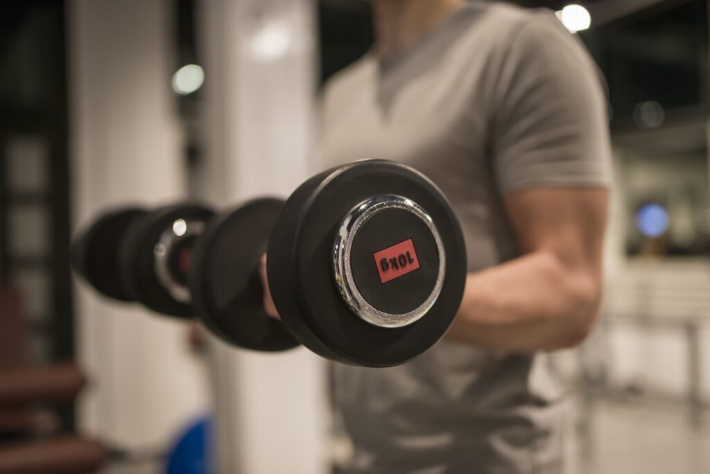 Muscular man training with red dumbbell in the gym